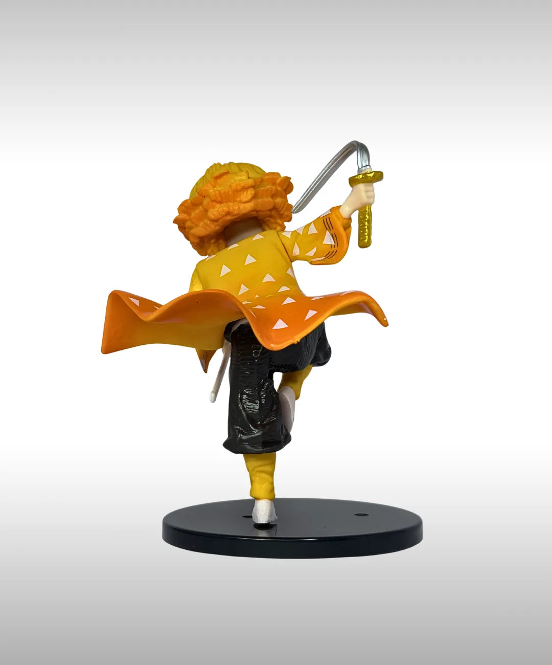 Figurine of a character with orange hair and yellow outfit holding a sword on a gray background