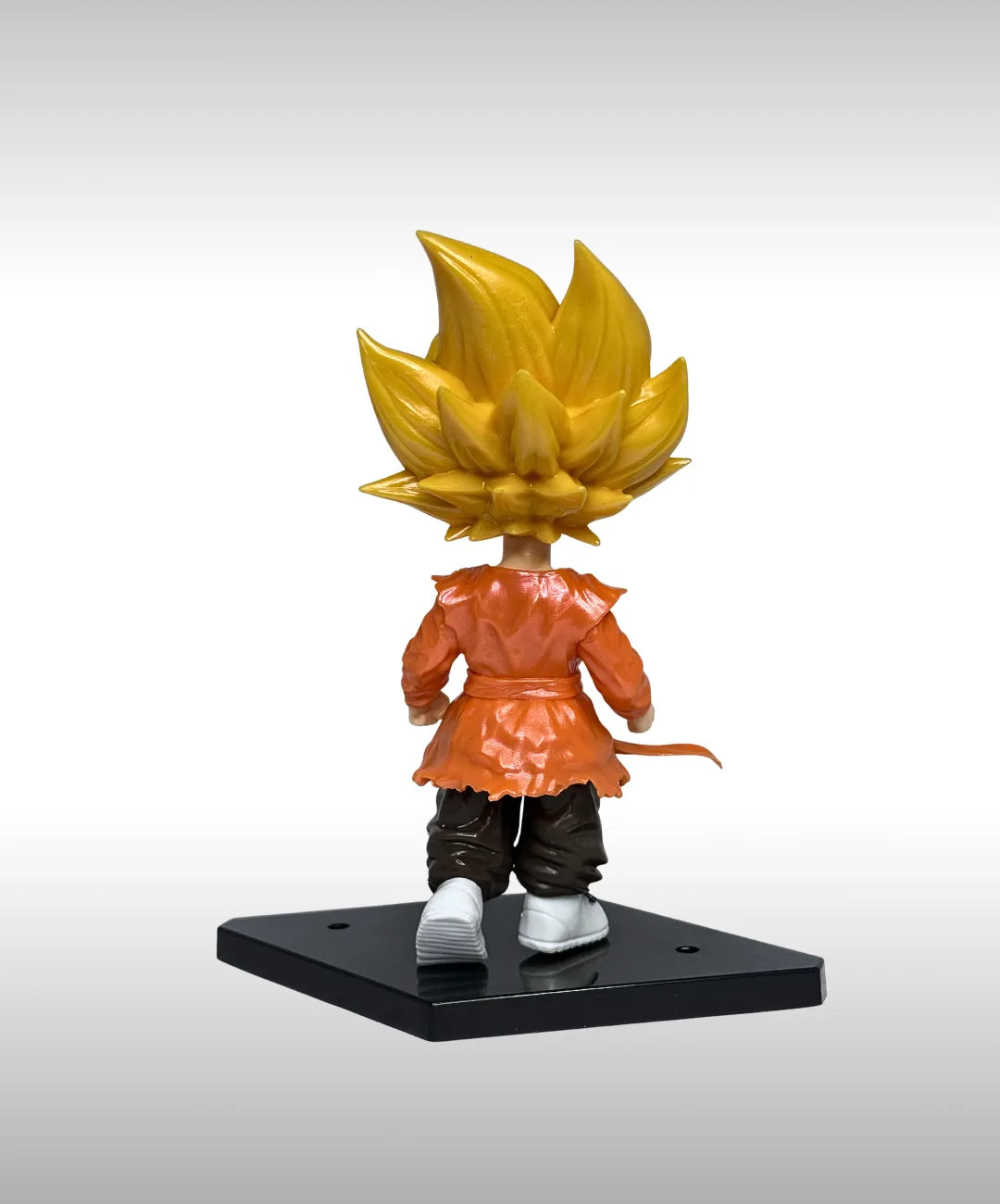 Action figure with yellow hair and orange outfit on a gray background