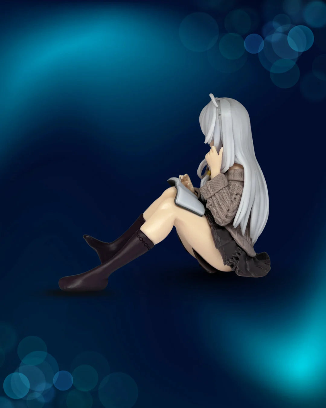 Figurine of a character with long white hair and brown outfit sitting on a dark blue background