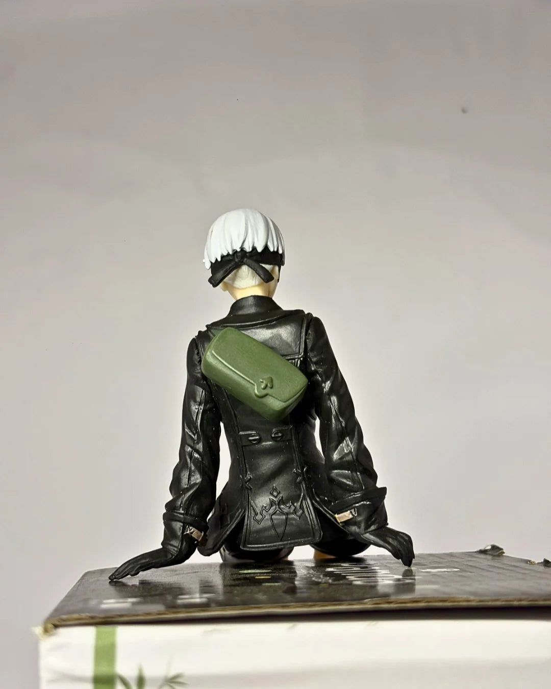 Figurine of a character in a black outfit with a green bag on a white background